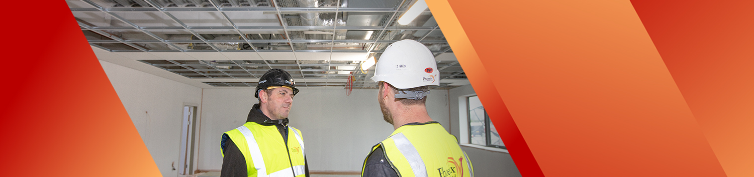 Two men in industrial room with suspended ceiling installation